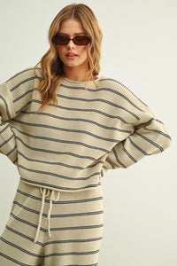 Cream-colored ribbed knit striped pattern long sleeve sweater with black horizontal stripes and drawstring waistband