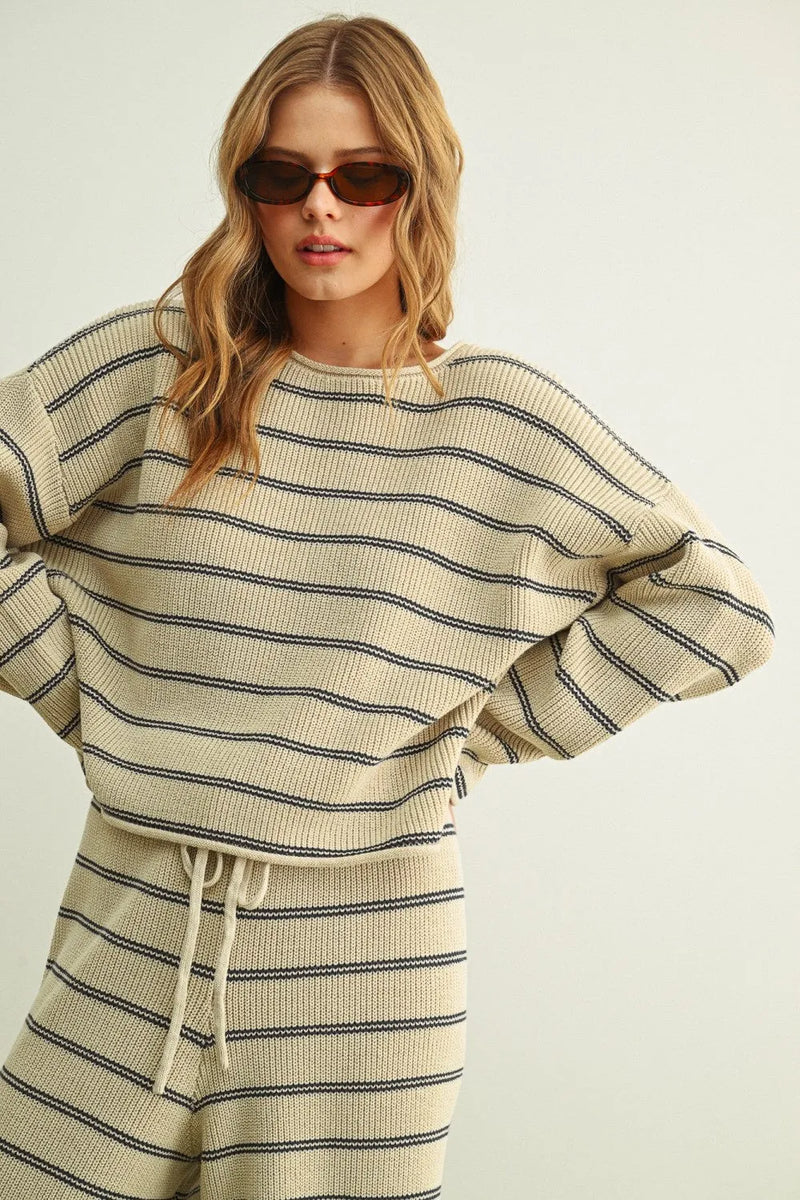 Cream-colored ribbed knit striped pattern long sleeve sweater with black horizontal stripes and drawstring waistband