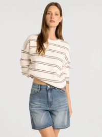 A cream-colored ribbed knit supply Ely sweater with black horizontal stripes and rolled-up sleeves