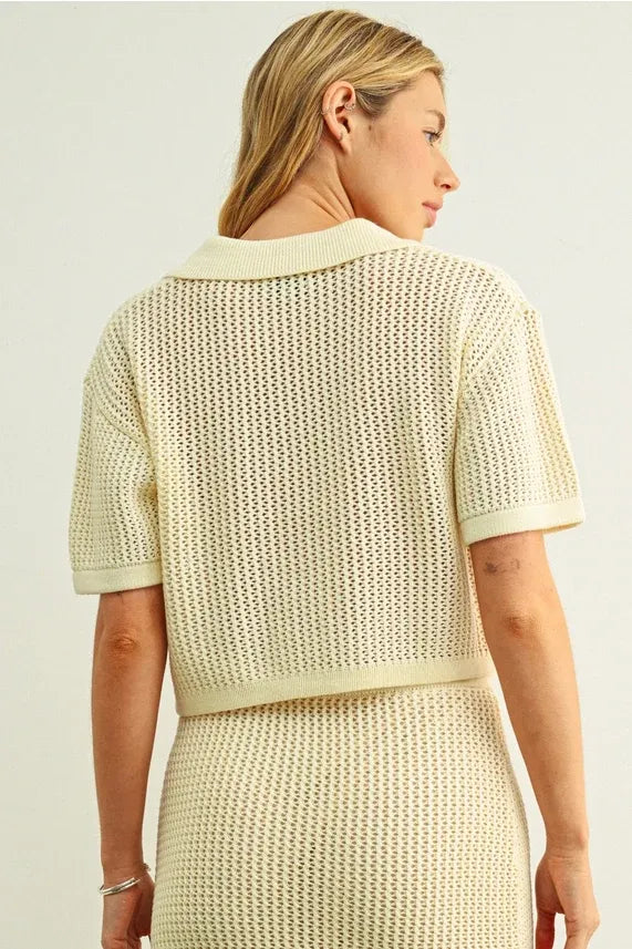 Cream-colored short-sleeved crochet v-neck cardigan with textured openwork pattern and ribbed v-neck collar
