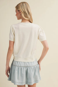 Cream-colored starburst pointelle puff sleeve top with short sleeves and textured knit pattern for stylish wear