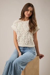 Cream-colored extended shoulder sweater top in knitted fabric featuring intricate diamond-patterned lacework