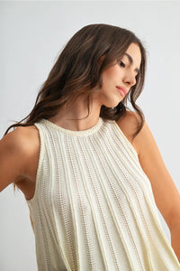 Cream-colored flared hem sleeveless knit top with vertical ribbed texture and subtle eyelet detailing