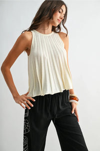 Cream-colored flared hem sleeveless knit top with vertical pleats and relaxed fit in soft knit fabric