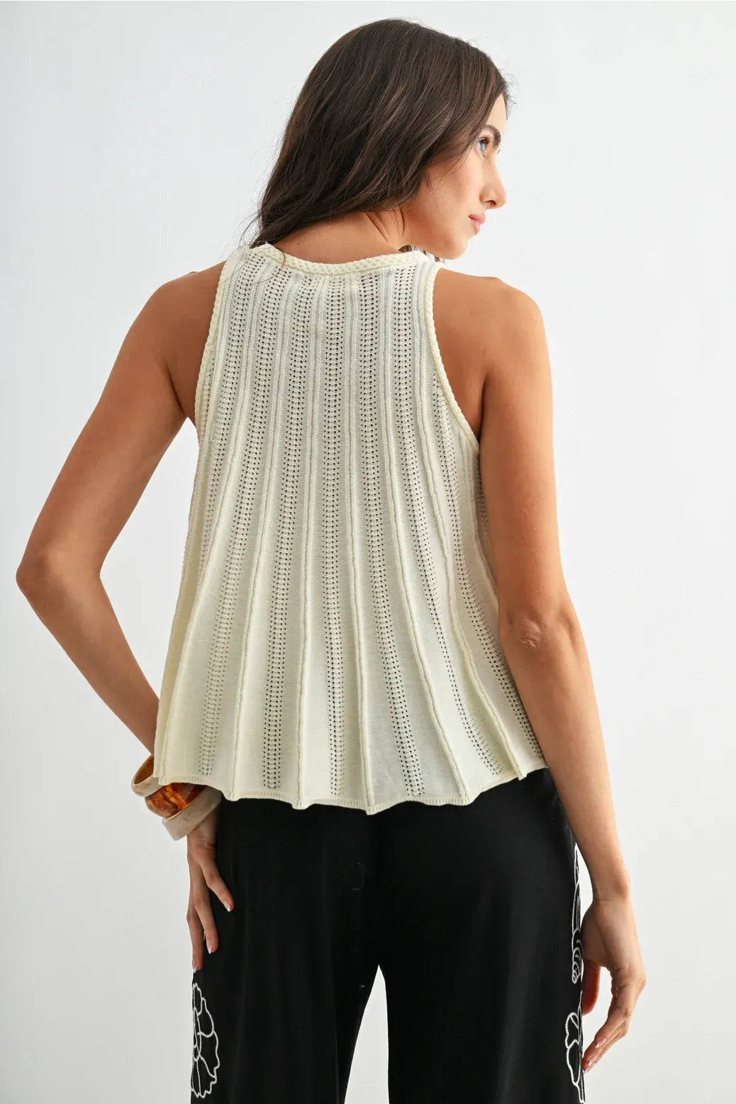 Cream-colored flared hem sleeveless knit top with vertical pleats and delicate openwork pattern