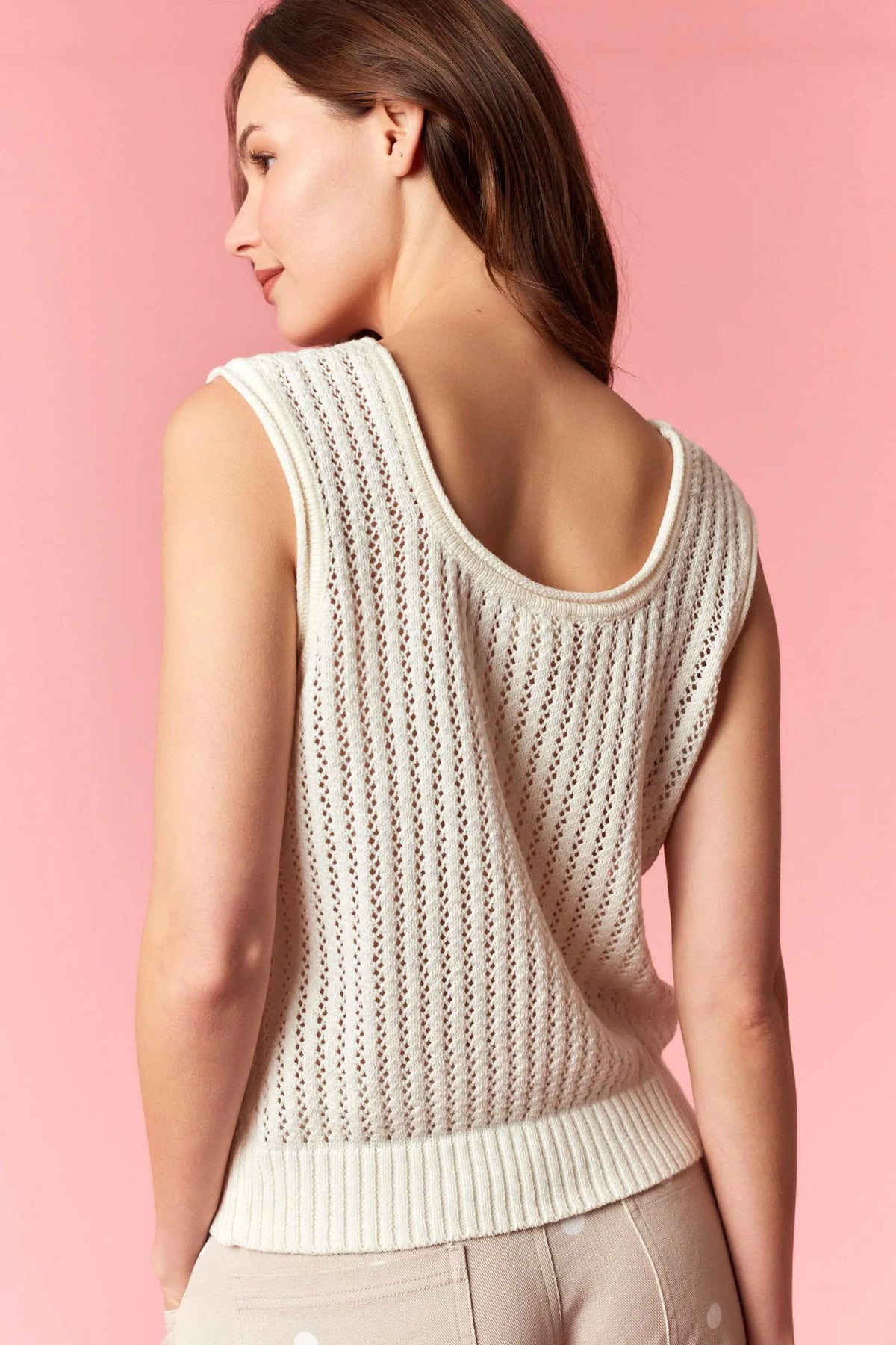 A cream-colored sleeveless america pointelle knit top with ribbed hem and back neckline shown from the back side