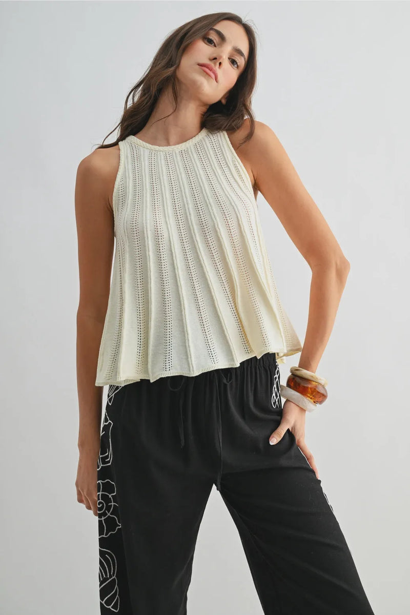 Cream-colored flared hem sleeveless knit top with pleated textured design and a soft flared hem detail