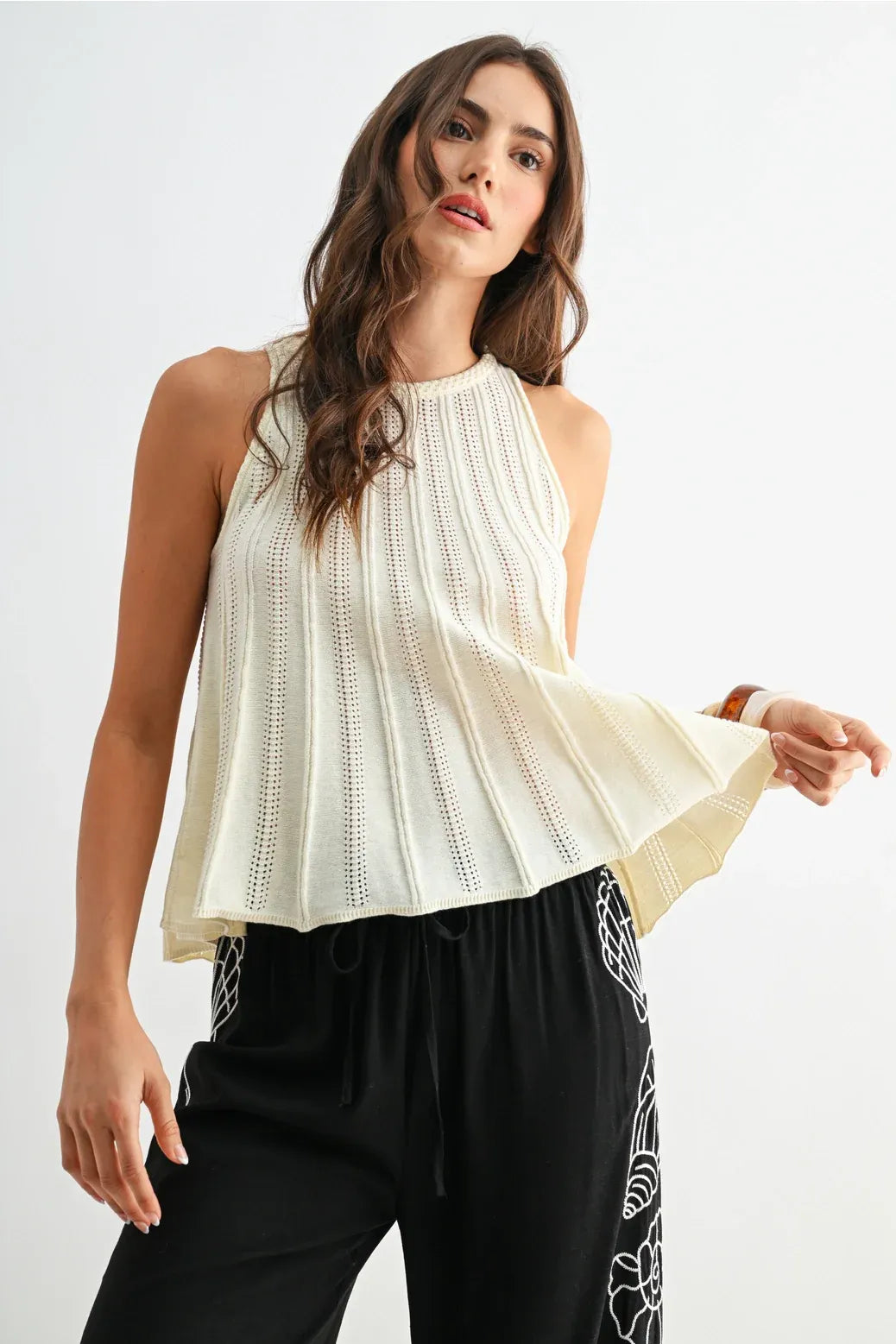 Cream-colored flared hem sleeveless knit top with pleated design and delicate eyelet detailing