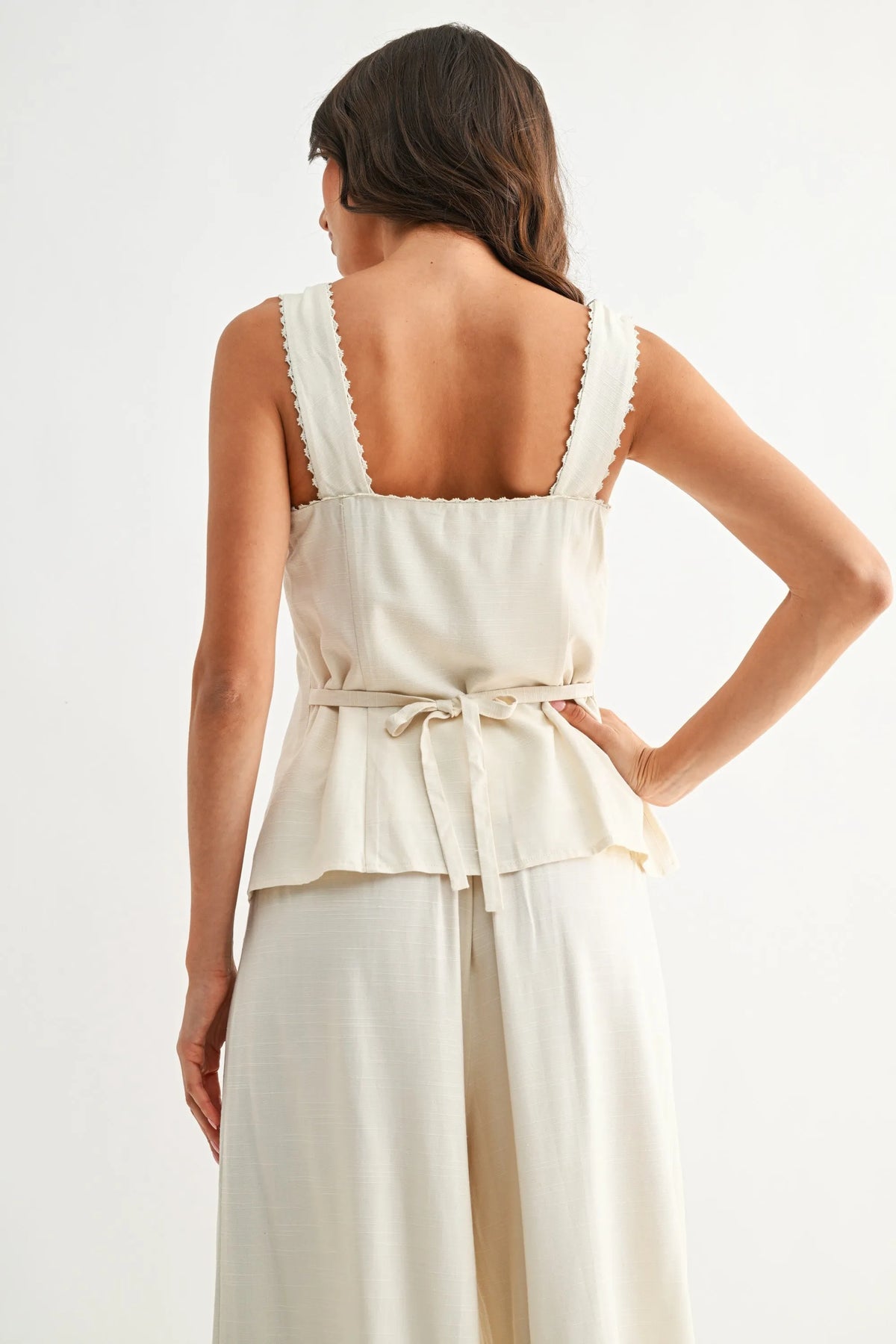 Cream-colored sweetheart button-down vest top with scalloped shoulder straps and tied waistband for stylish wear