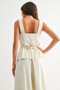 Cream-colored sweetheart button-down vest top with scalloped shoulder straps and tied waistband for stylish wear
