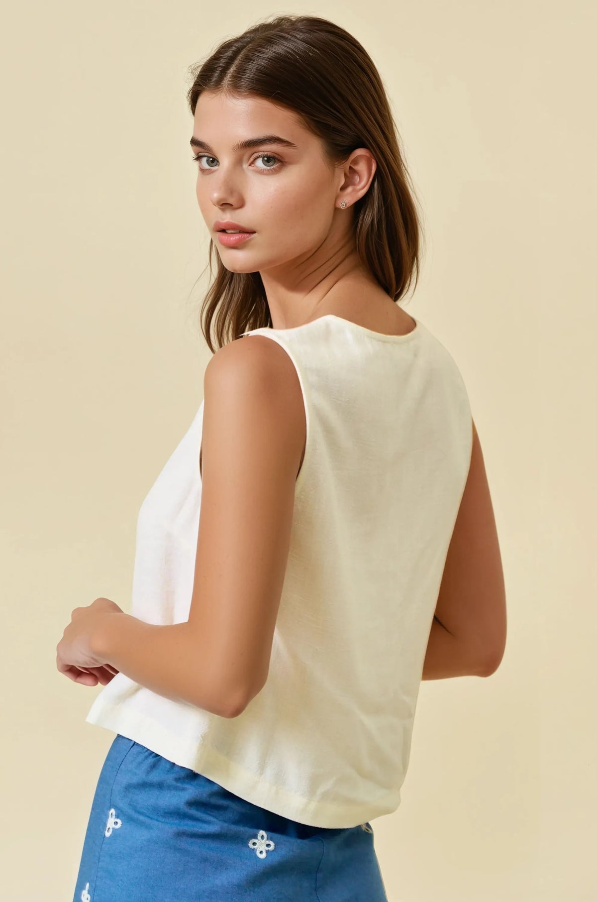 Cream-colored viscose blend button sleeveless top with soft flowing fabric and gathered detailing at the hem
