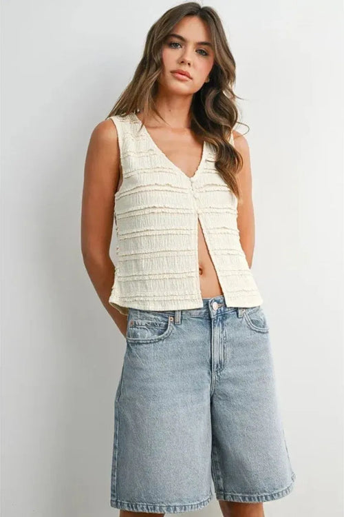 A cream-colored sleeveless textured button front top with v-neck and horizontal ruched detailing for women’s boho chic clothing