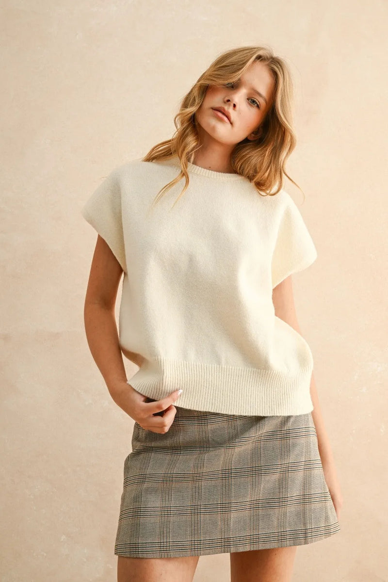Cream-colored loose fit short sleeve sweater top in soft knit with ribbed hem for relaxed casual wear