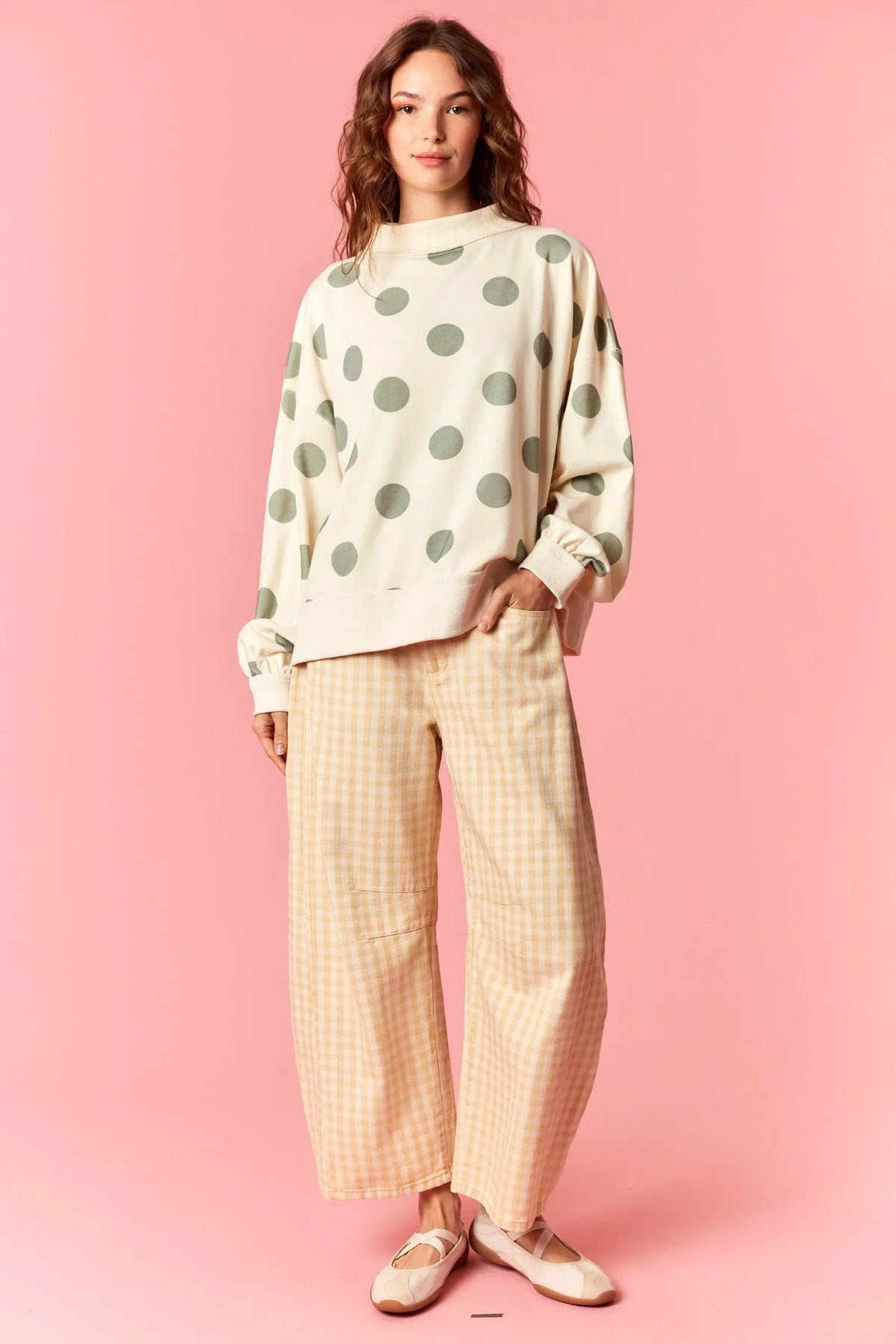 A cream-colored sweatshirt with oversized olive-green polka dots paired with washed gingham printed twill barrel pants