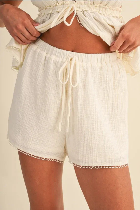 Cream-colored gauze picot lace short with textured cotton fabric drawstring waist and delicate scalloped hem