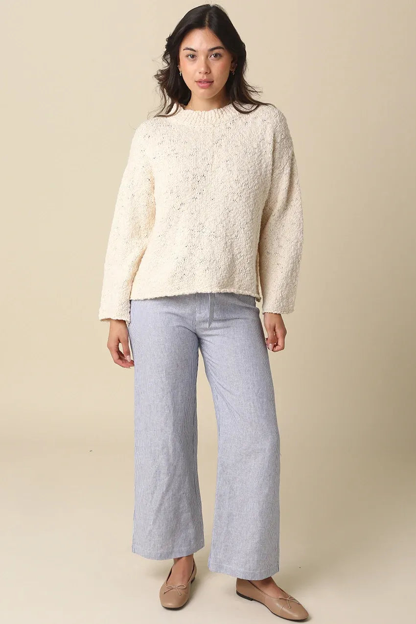 Cream-colored textured knit sweater with relaxed fit and long sleeves styled with malia striped tie waist pants