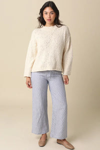 Cream-colored textured knit sweater with relaxed fit and long sleeves styled with malia striped tie waist pants