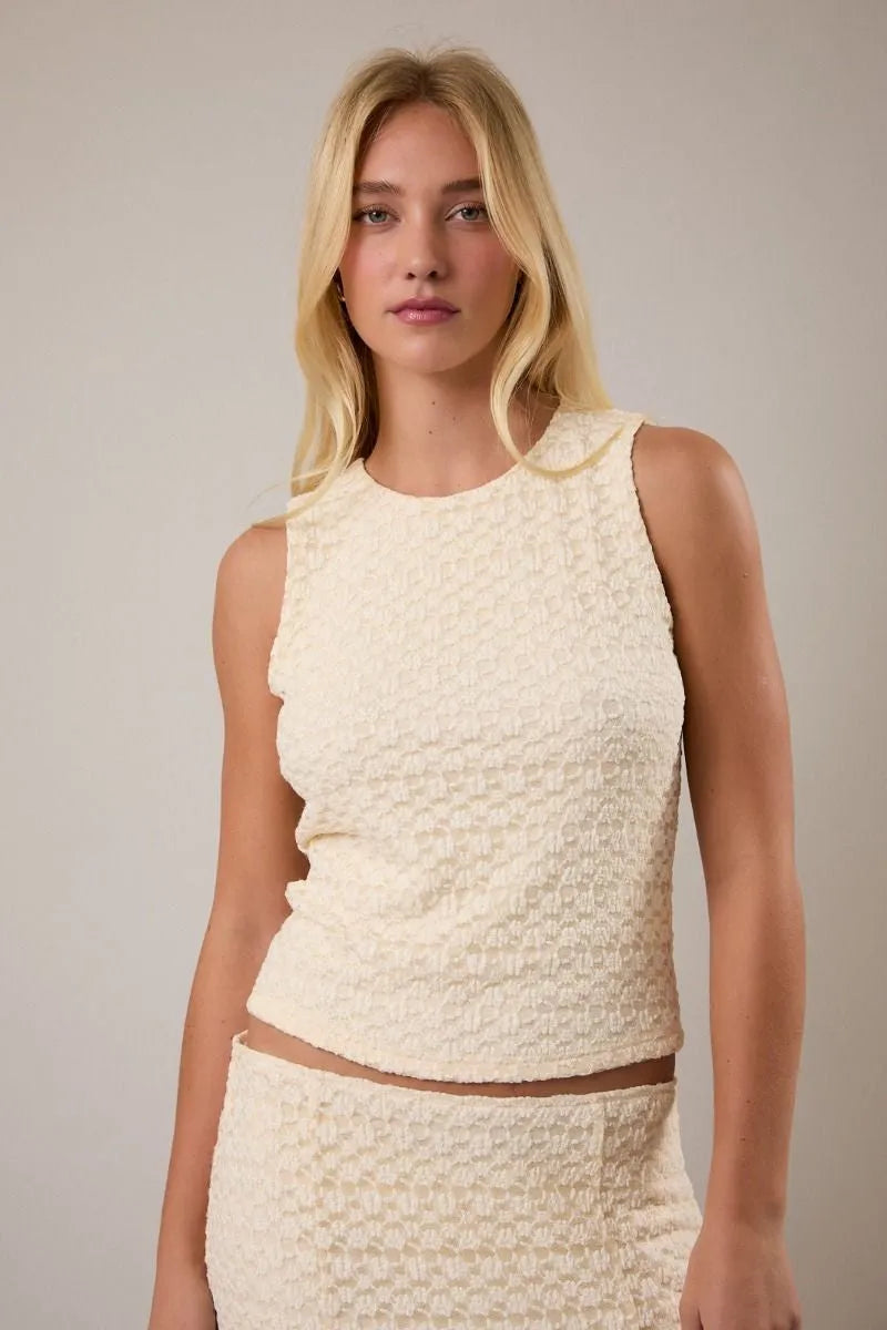 Cream-colored round neck lace sleeveless top featuring a textured fabric with subtle geometric pattern