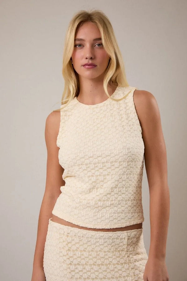 Cream-colored round neck lace sleeveless top featuring a textured fabric with subtle geometric pattern