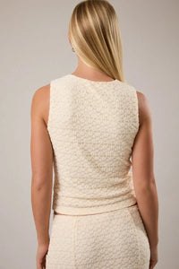 Cream-colored round neck lace sleeveless top with textured fabric and fitted ruched waistband for elegant wear