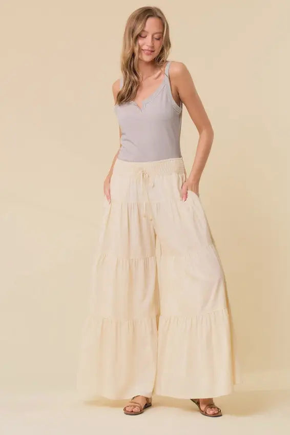 Cream-colored tiered wide pants with smocked drawstring waist and flowy tiered wide design for comfortable wear
