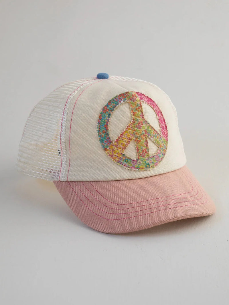 Cream-colored canvas trucker hat with a pink brim and a colorful glittery peace sign patch on the front