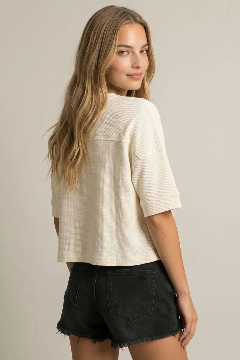 Cream-colored waffle-knit short-sleeved top with a relaxed fit.