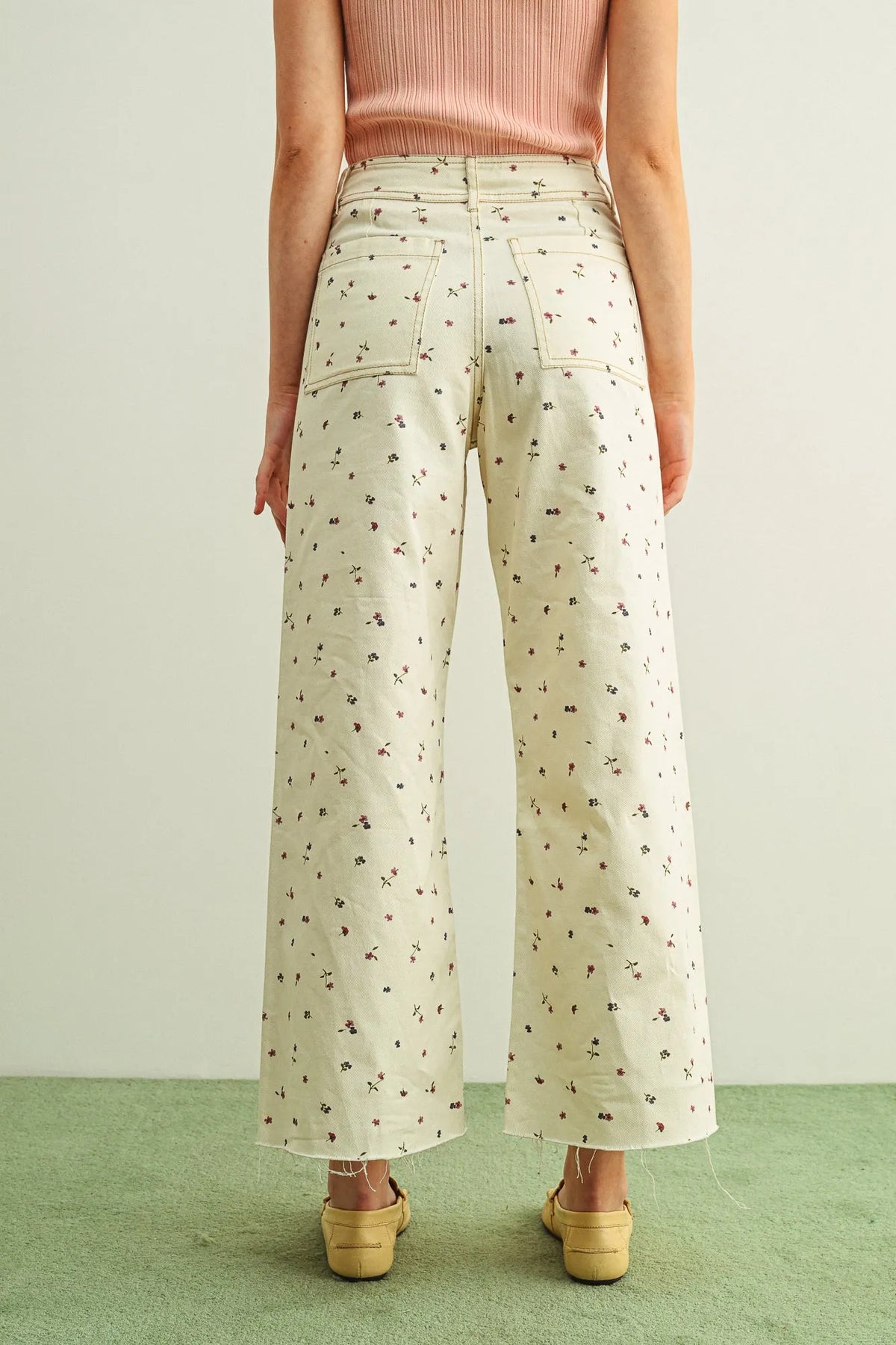 Cream-colored floral print stretched pants with wide legs and frayed hems in delicate print stretched fabric