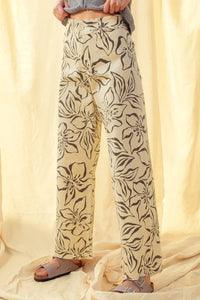 Cream-colored floral print stretch wide leg pants with bold black pattern