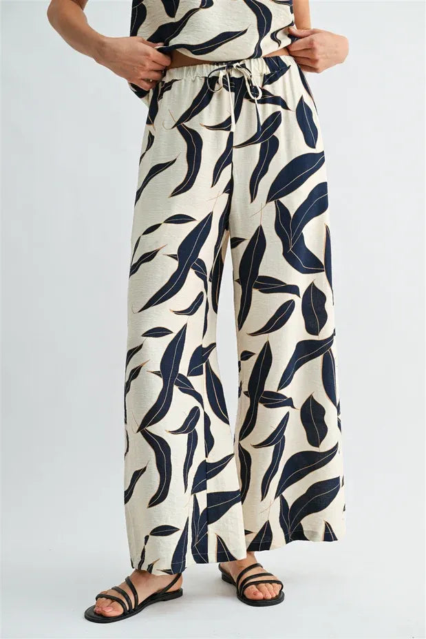 Cream-colored wide leg pants with bold navy leaf print and elastic waist drawstring for comfortable fit