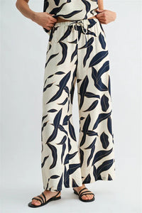 Cream-colored wide leg pants with bold navy leaf print and elastic waist drawstring for comfortable fit