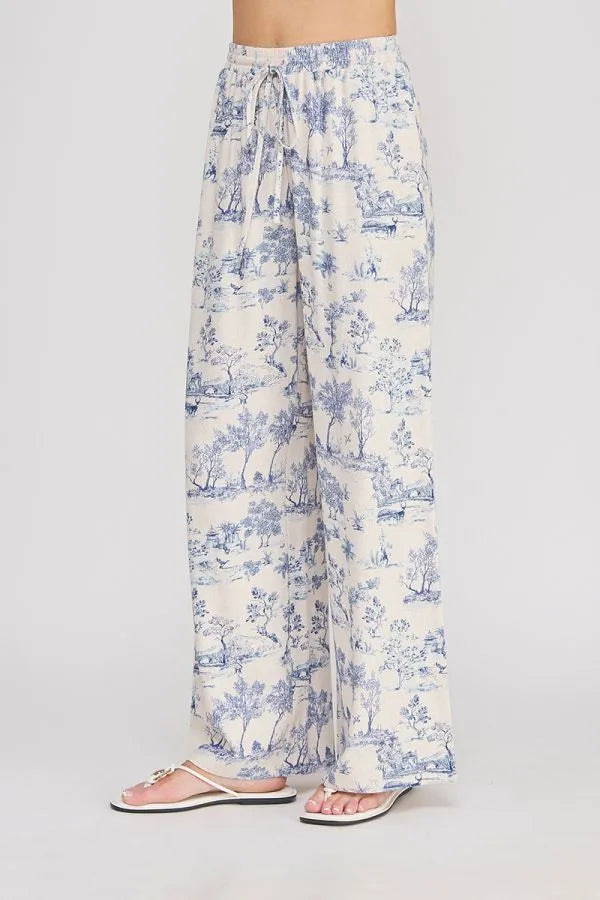 Cream-colored wide leg pants with blue toile print, lightweight fabric, and elastic tie waist for comfort and style