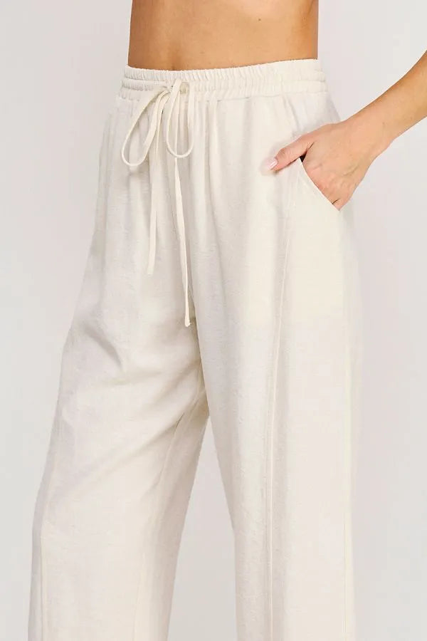 Cream-colored rayon linen blend relaxed tapered pants with elastic waistband and matching drawstring for comfort