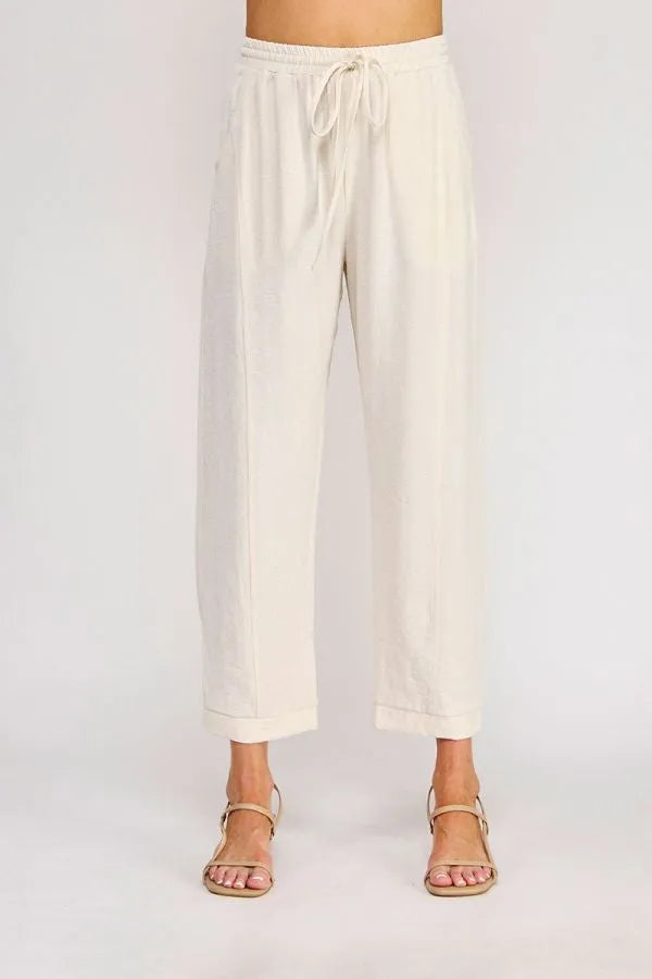 Cream-colored rayon linen blend relaxed tapered pants with wide legs, drawstring waist, and rolled cuffs