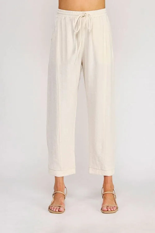 Cream-colored rayon linen blend relaxed tapered pants with wide legs, drawstring waist, and rolled cuffs