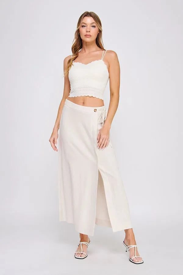 Cream-colored wide-leg trousers with side slit and tie-side waistband complementing fine lace pattern scallop bralette