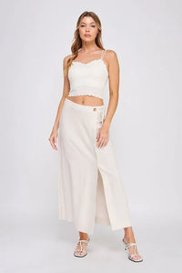 Cream-colored wide-leg trousers with side slit and tie-side waistband complementing fine lace pattern scallop bralette