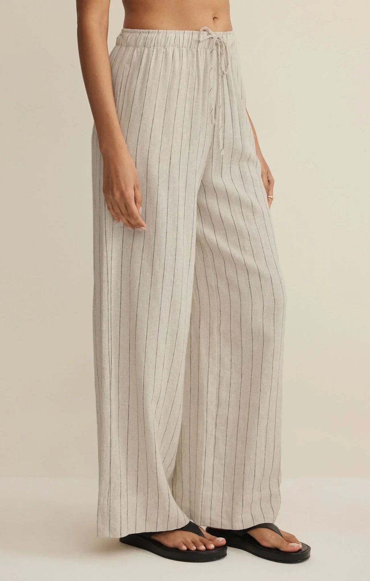 Cream-colored henri striped wide leg pants with thin black vertical stripes and elastic waistband with drawstring