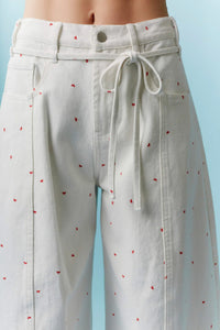 Cream-colored high waist wide-leg trousers with subtle mini bow print embroidery and matching drawstring waistband