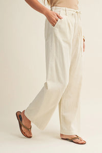 Cream-colored wide leg dyed trousers with pleated waist and drawstring for a comfortable fit