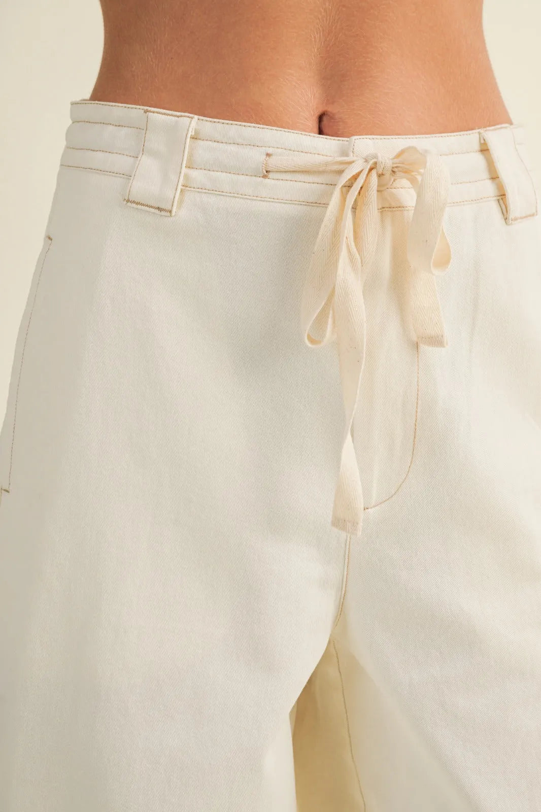 Cream-colored pull on baggy fit pants with wide legs drawstring waistband and subtle stitching details
