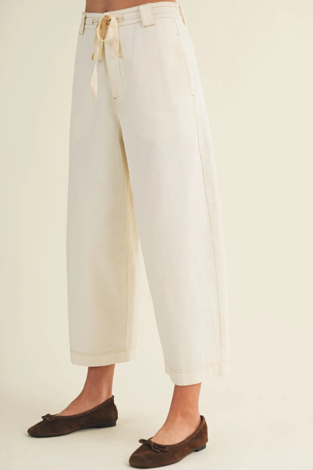 Cream-colored baggy fit pants with wide legs, drawstring waist, and rolled cuffs in a pull on style