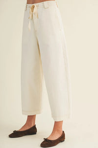 Cream-colored baggy fit pants with wide legs, drawstring waist, and rolled cuffs in a pull on style