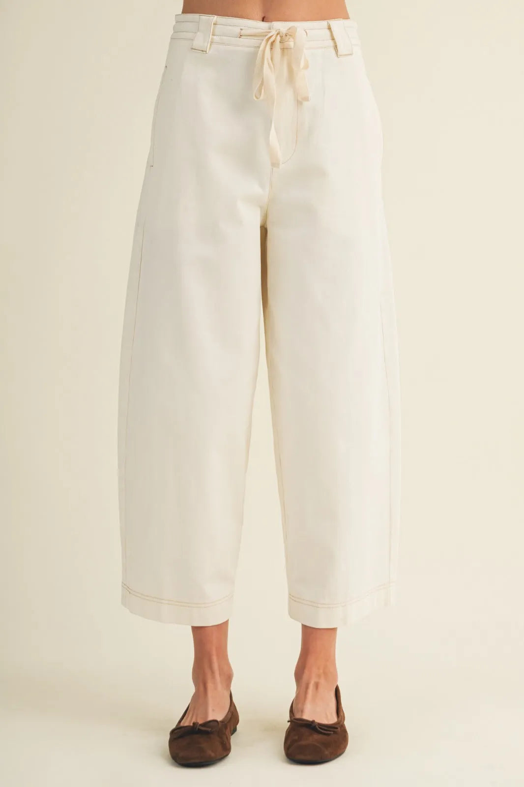 Cream-colored pull on baggy fit pants with wide-leg design drawstring waist and rolled cuffs for casual wear