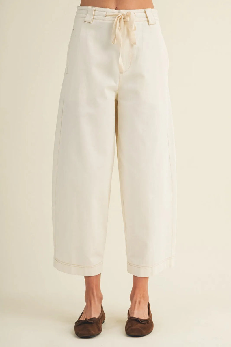 Cream-colored pull on baggy fit pants with wide-leg design drawstring waist and rolled cuffs for casual wear