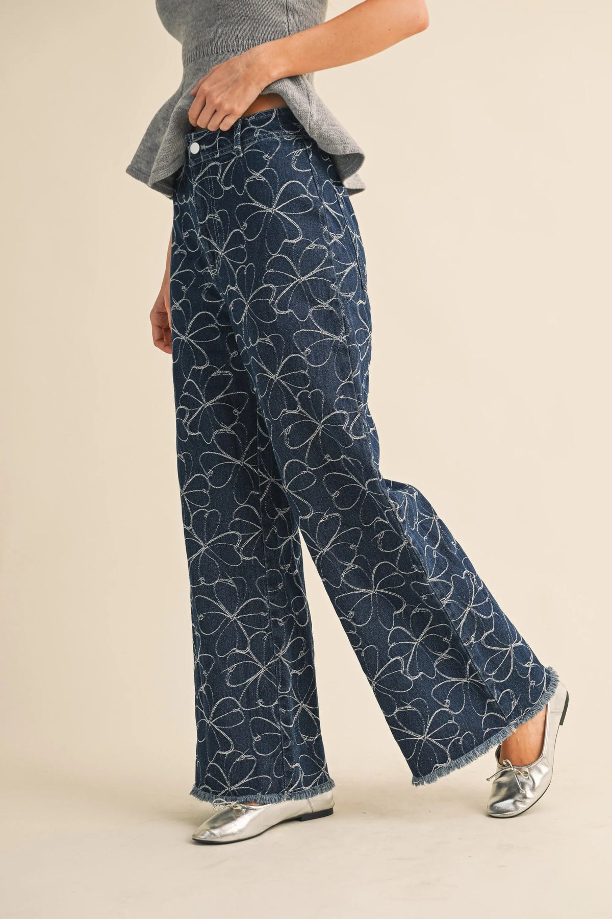 Dark blue denim wide-leg pants with white floral design and distressed hem for a stylish casual look