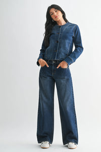 A dark blue denim jacket with button-front closure and rolled cuffs paired with low rise baggy wide denim jeans