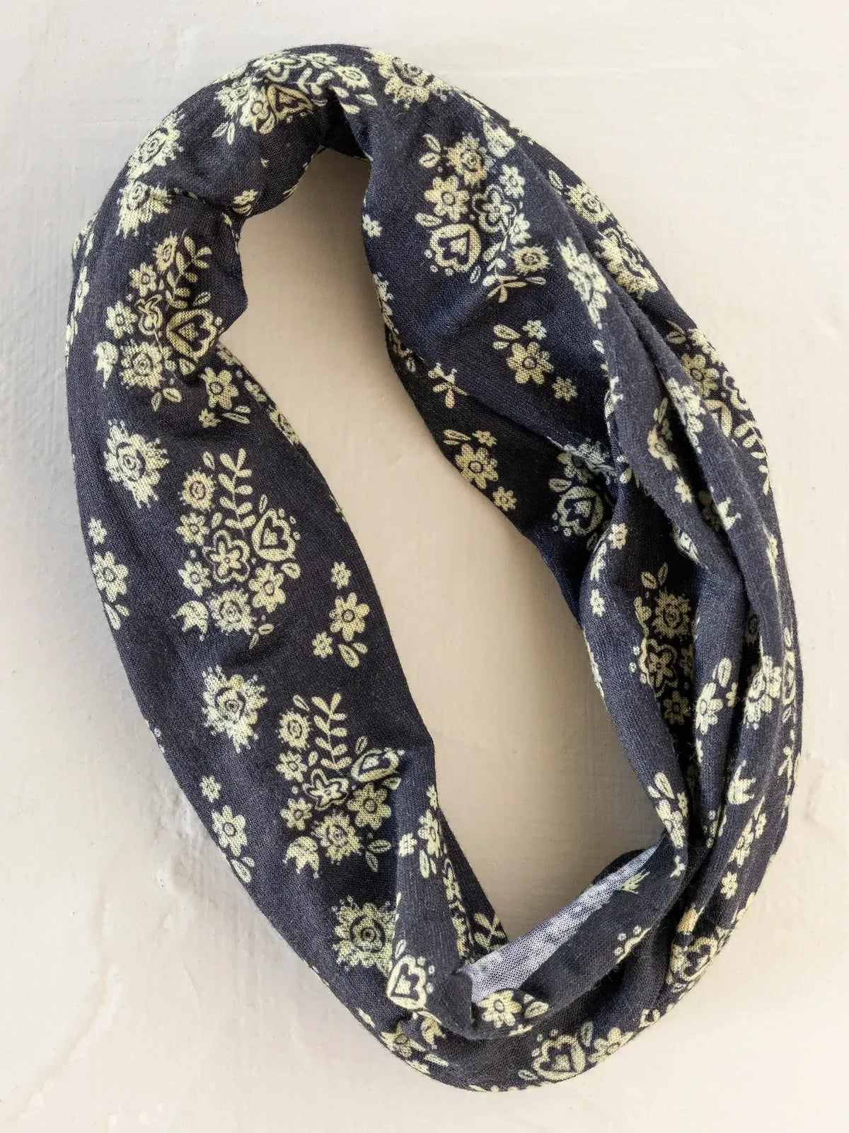 Dark blue infinity scarf with cream floral pattern styled as a boho bandeau headband for versatile wear