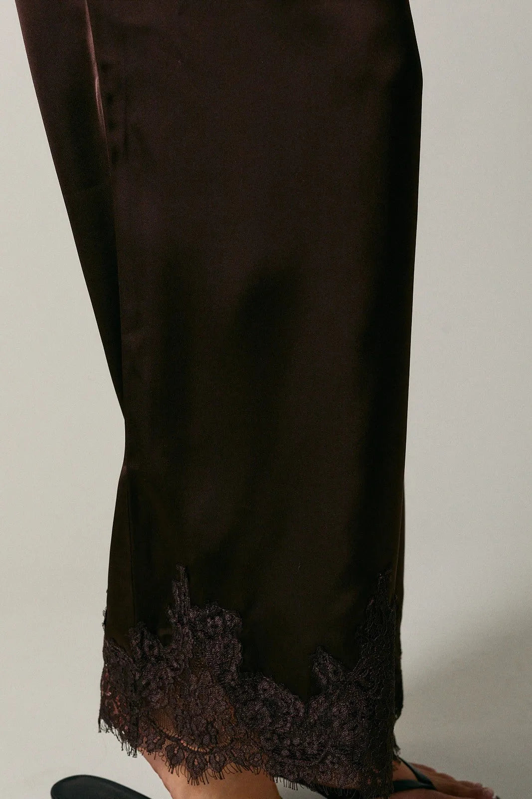 Dark brown satin wide leg pants with elastic waist lace and delicate black lace trim along the hem