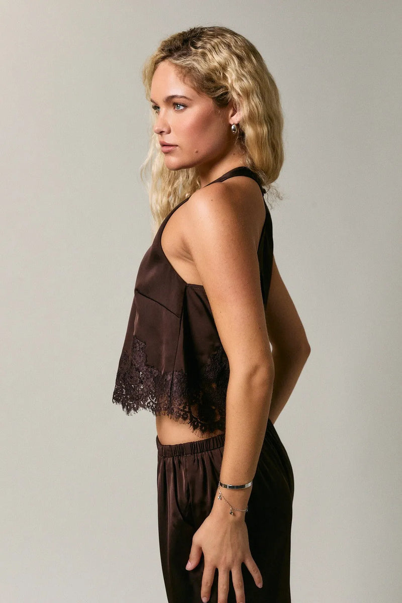 A dark brown satin halter neck sleeveless top with delicate black lace trim detailing along the hem